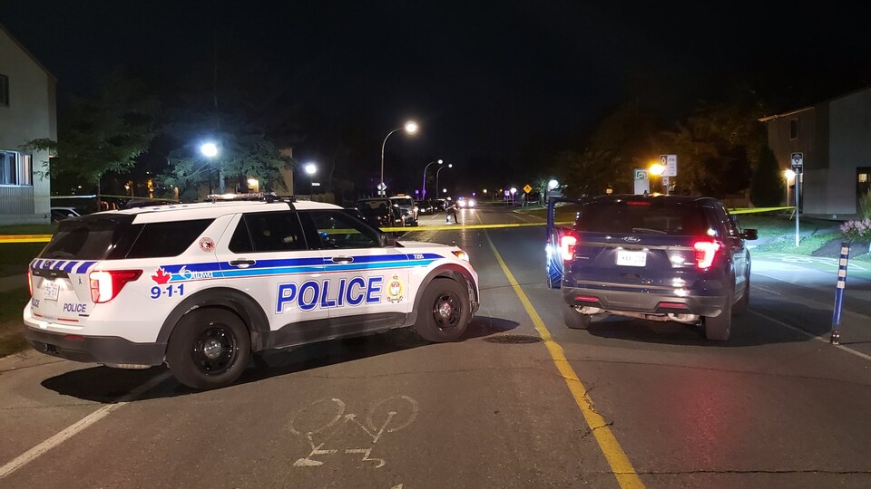 Un véhicule utilitaire sport de la police d'Ottawa stationné dans la rue près d'un cordon de sécurité la nuit.