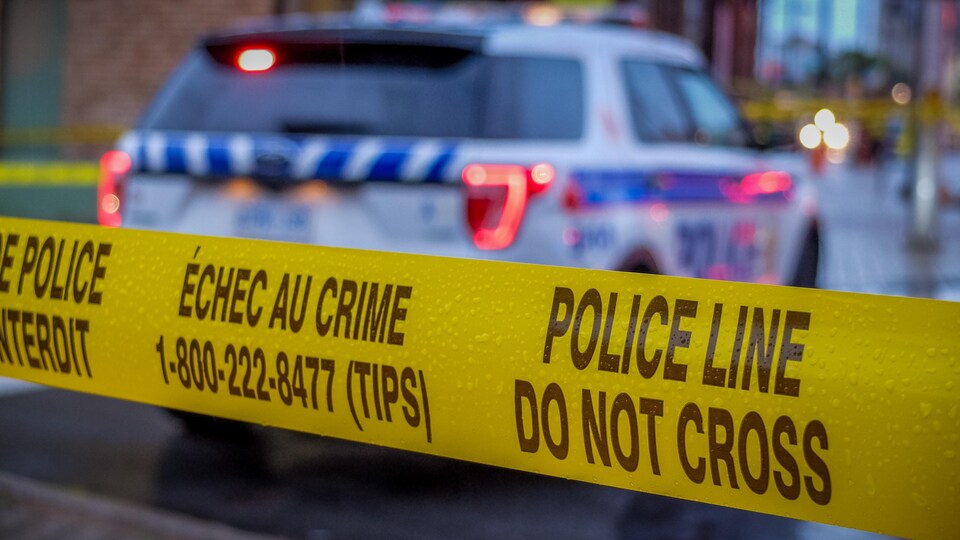 Un ruban jaune devant une autopatrouille de la police.