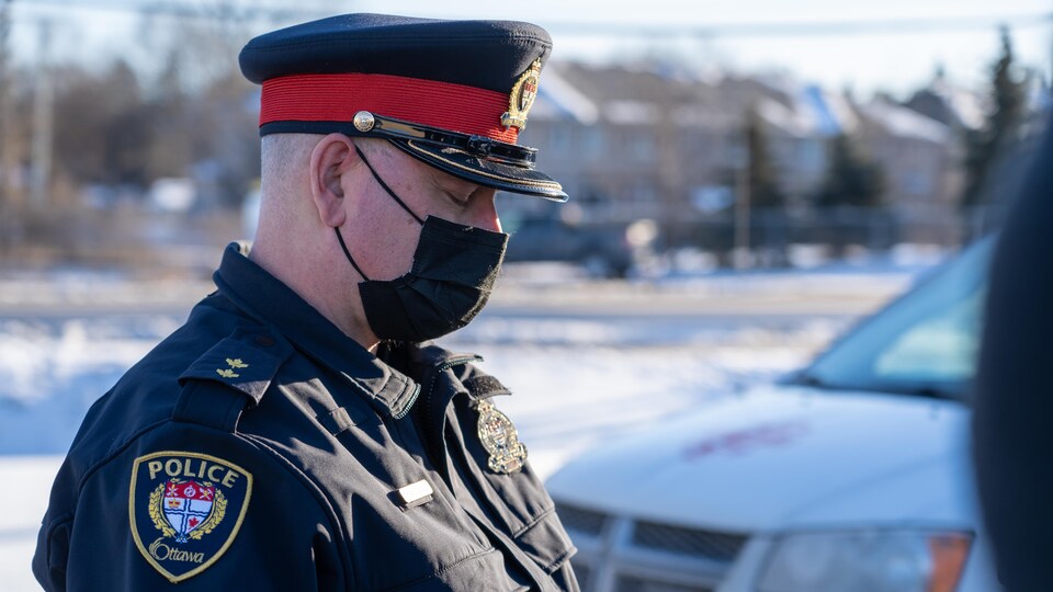 Un policier du Service de police d'Ottawa, les yeux fermés, tête vers le bas.