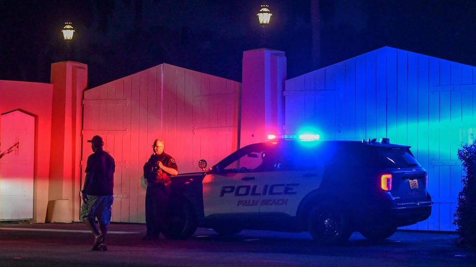 Une voiture et un agent de la police de Palm Beach devant les clôtures de la maison 