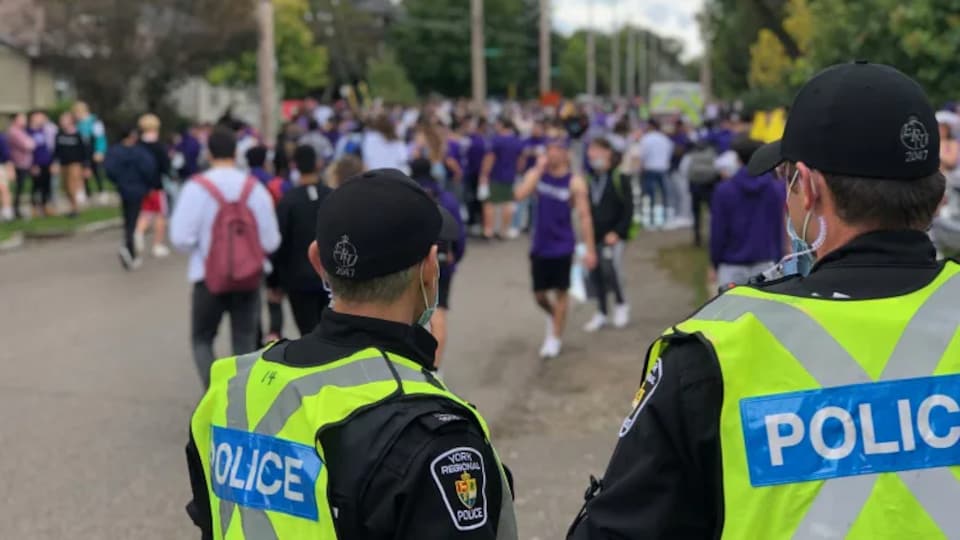 Des policiers qui surveillent des étudiants rassemblés en grand nombre dans la rue.