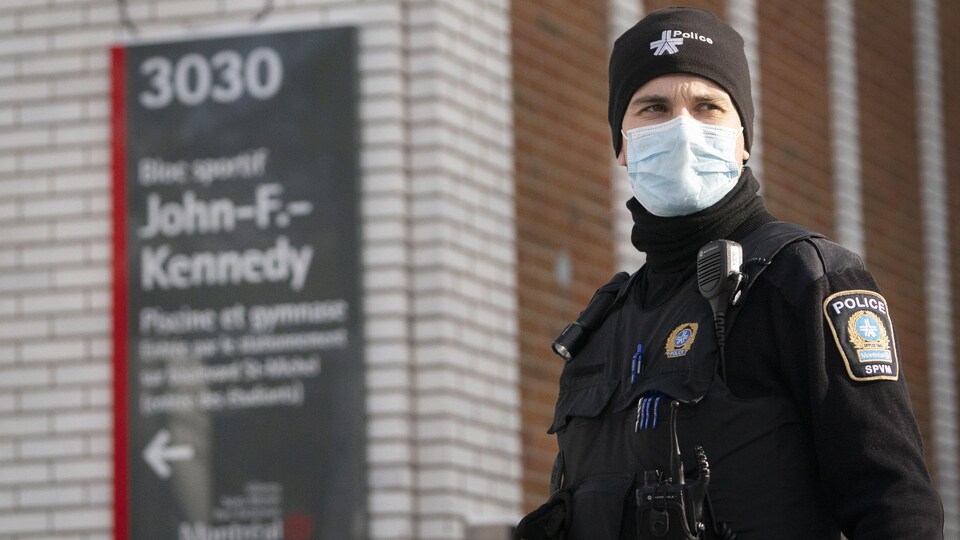 Un agent du Service de police de la Ville de Montréal devant l'école John-F.-Kennedy en hiver.