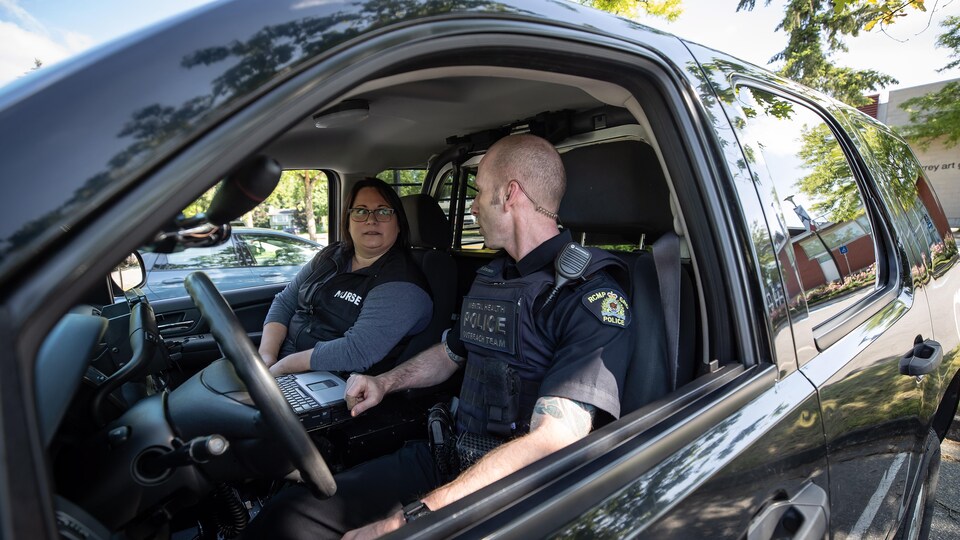 Tina Baker et Scotty Schumann assis dans une voiture de police