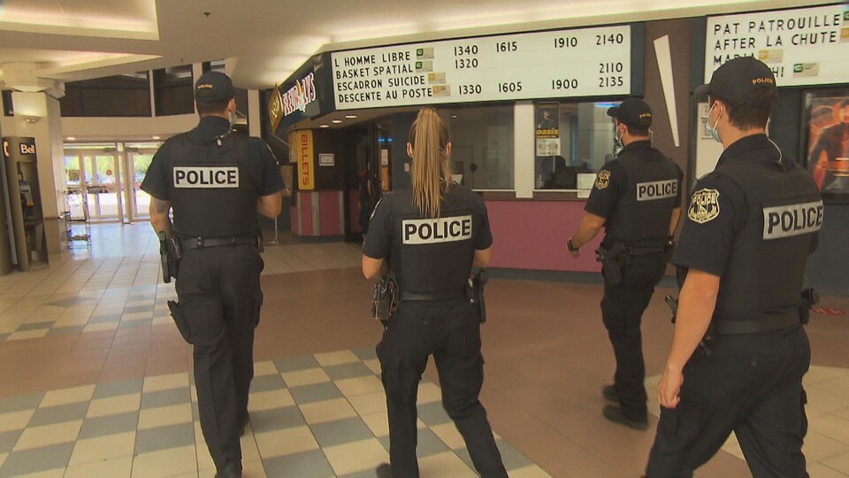 Quatre policiers marchent en direction du Cinéma Fleur de Lys.