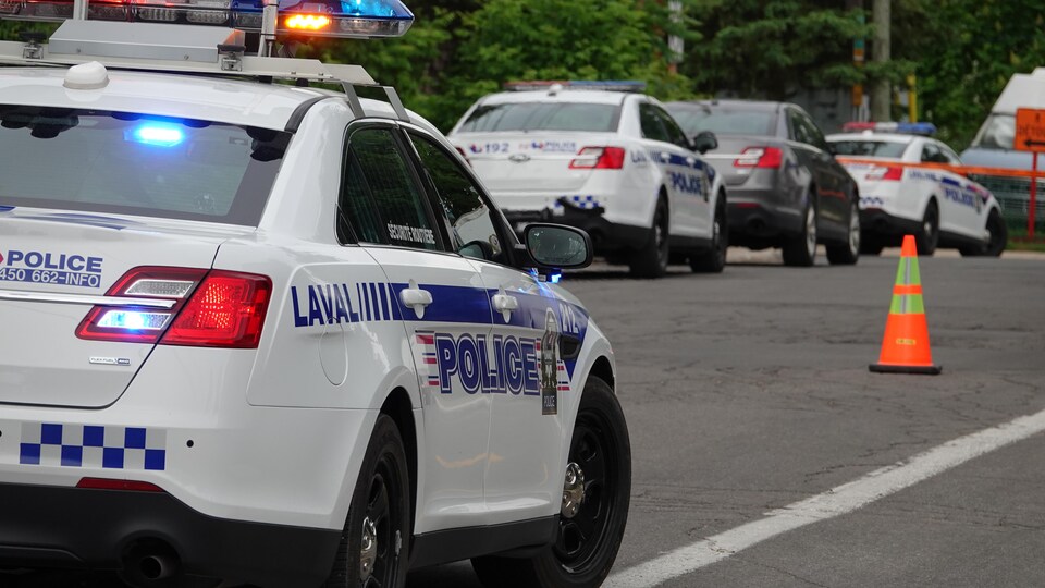 Une voiture de patrouille avec ses gyrophares allumés stationnée.