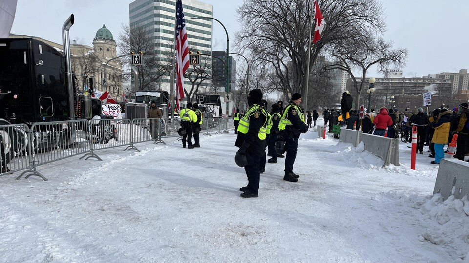 Des policiers en ligne entre les deux groupes devant le Palais législatif à Winnipeg. 