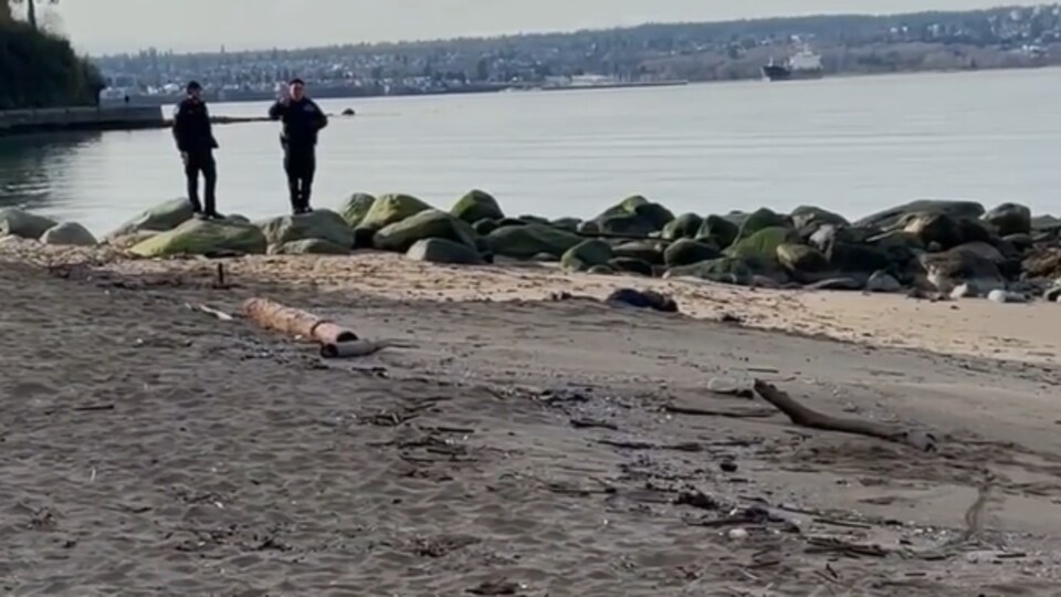 Deux policiers de Vancouver attendent les services médicaux près d'un corps à Third Beach sur le Sea Wall.