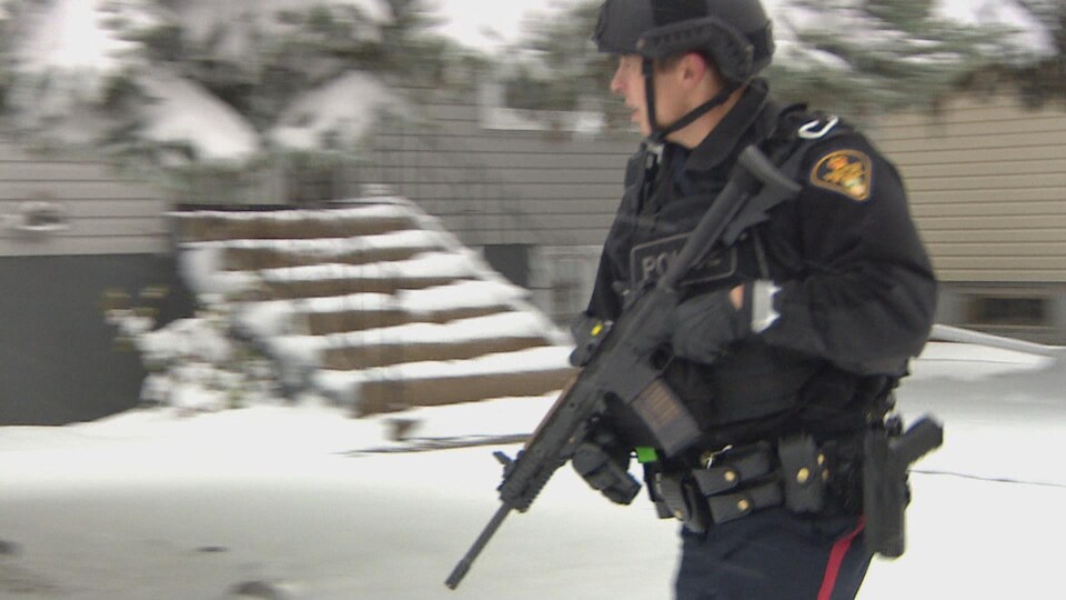 Un policier porte une arme dans ses mains.