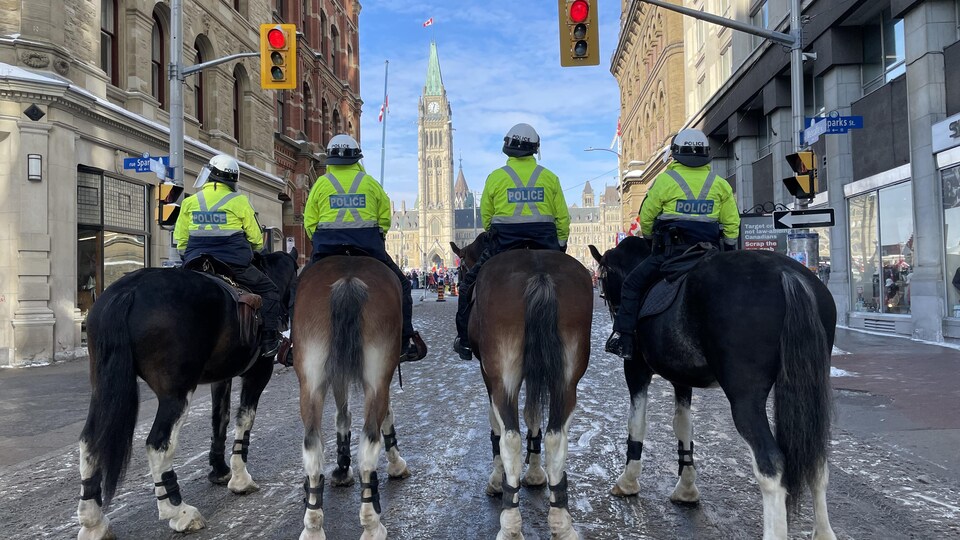 Quatre policiers sur des chevaux devant le parlement sur la rue Metcalfe, à Ottawa.