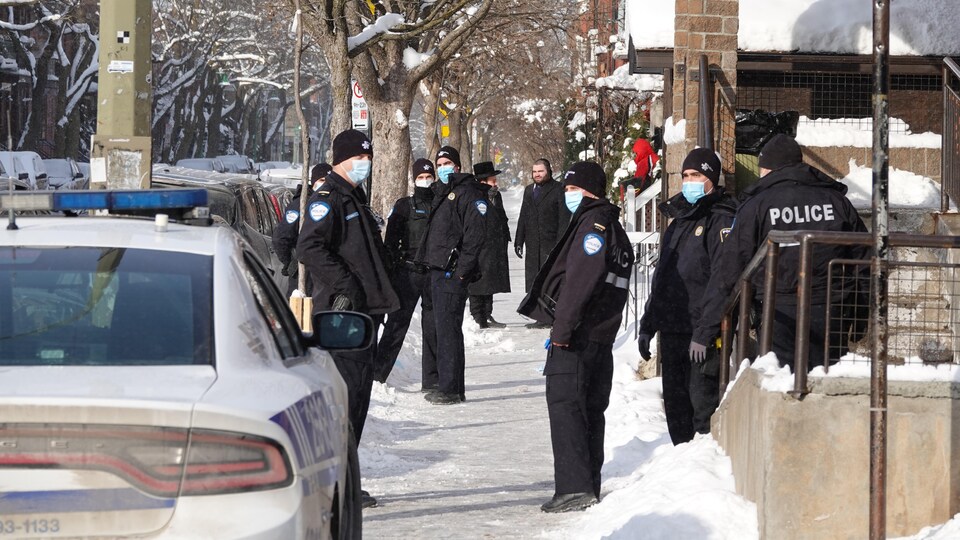 Une dizaine de policiers dans une rue enneigée d'Outremont. 