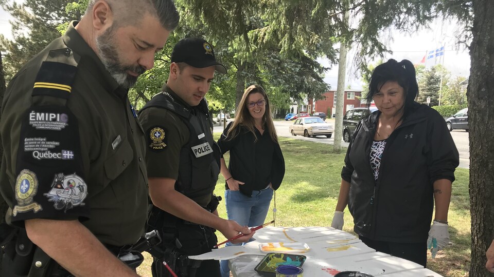 Des policiers du Poste de police communautaire mixte autochtone (PPCMA) de Val-d'Or participent à la confection de l'oeuvre collective au parc Bérard.