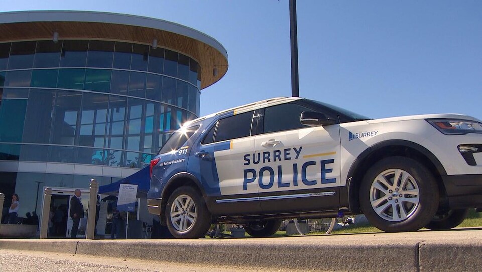 Une voiture de police de Surrey devant l'hôtel de ville, un édifice en verre.