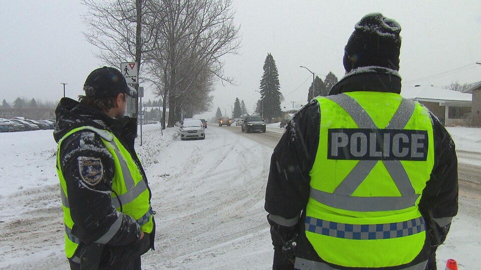 Deux policiers de dos surveillent la circulation.