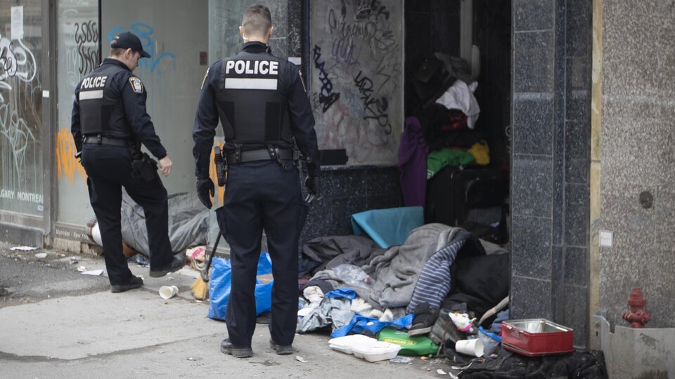 Deux policiers près d'un espace occupé par des sans-abri à Montréal.
