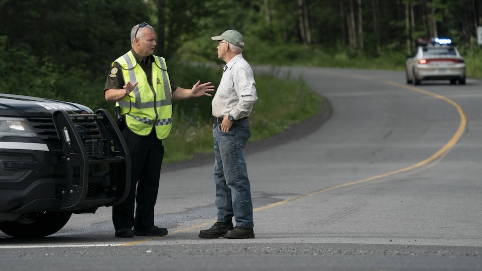 Un policier discute avec un homme sur une route de campagne.