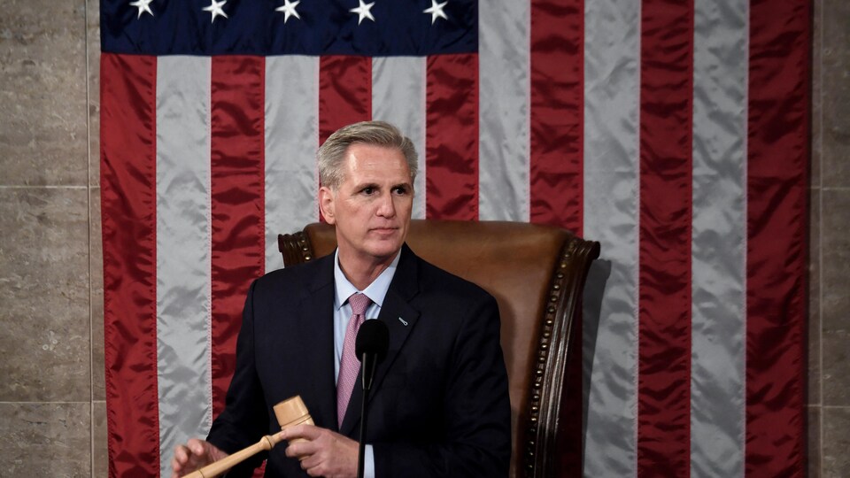 Kevin McCarthy holds the speaker's cowl in front of an American flag.