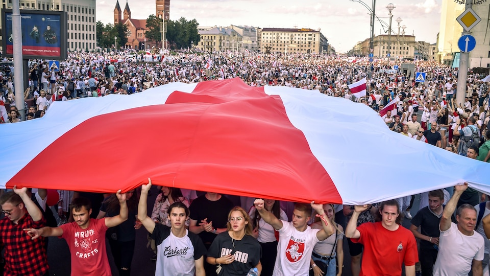 Une foule de manifestants sous un drapeau à Minsk.