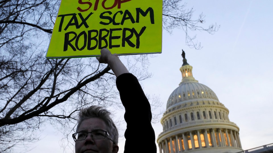 Une manifestante brandit une pancarte contre la réforme fiscale devant le Capitole, à Washington.