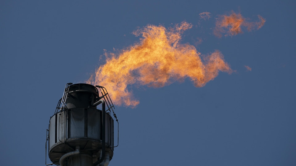 Une flamme s'échappe d'une cheminée d'une raffinerie.