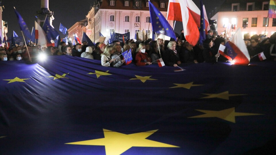 Des manifestants brandissent des drapeaux de la Pologne et de l'Union européenne.