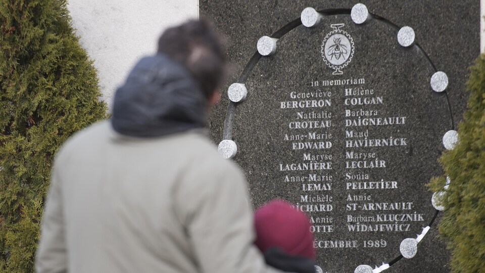 Un homme et un enfant devant le mémorial de Polytechnique.