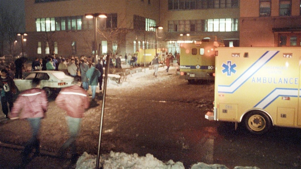 Une foule et plusieurs ambulances à l'extérieur d'un bâtiment.