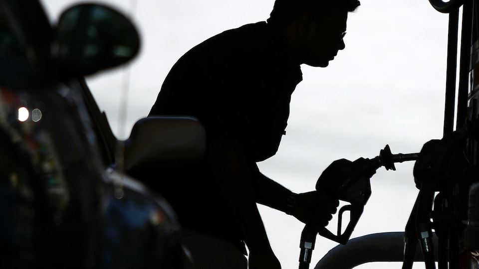 Silhouette d'un homme devant une pompe à essence.