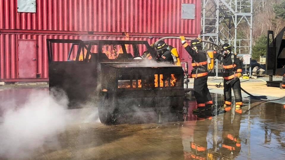 Firefighters put out a fire in a burning fake car.