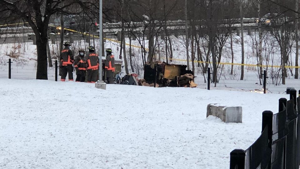 Des pompiers près du campement brûlé.