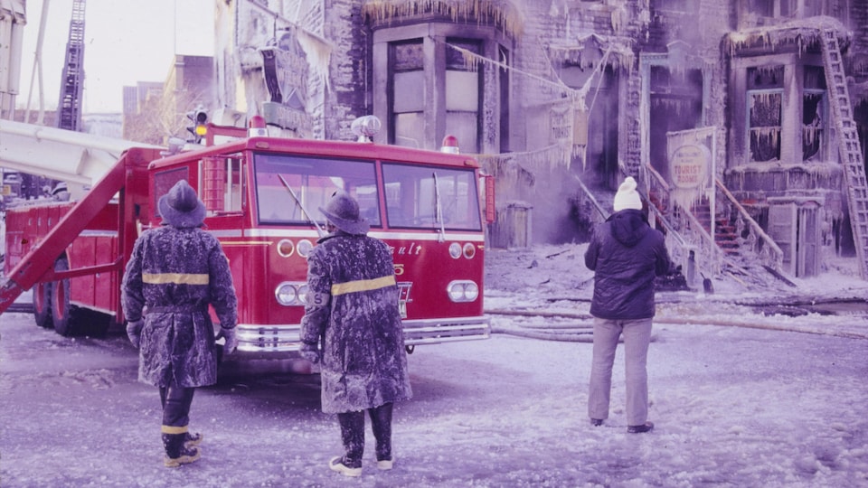 Pompiers montréalais près d'un camion après l'extinction d'un feu. Scène hivernale avec beaucoup de glace.