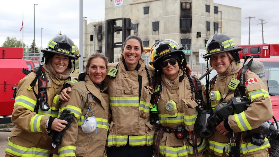 Cinq pompières d'Edmonton portant leur uniforme de travail posent pour une photo.