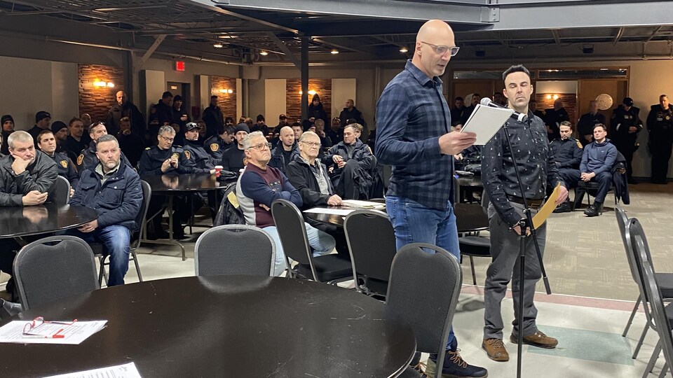 Deux hommes qui s'adressent à des élus. 