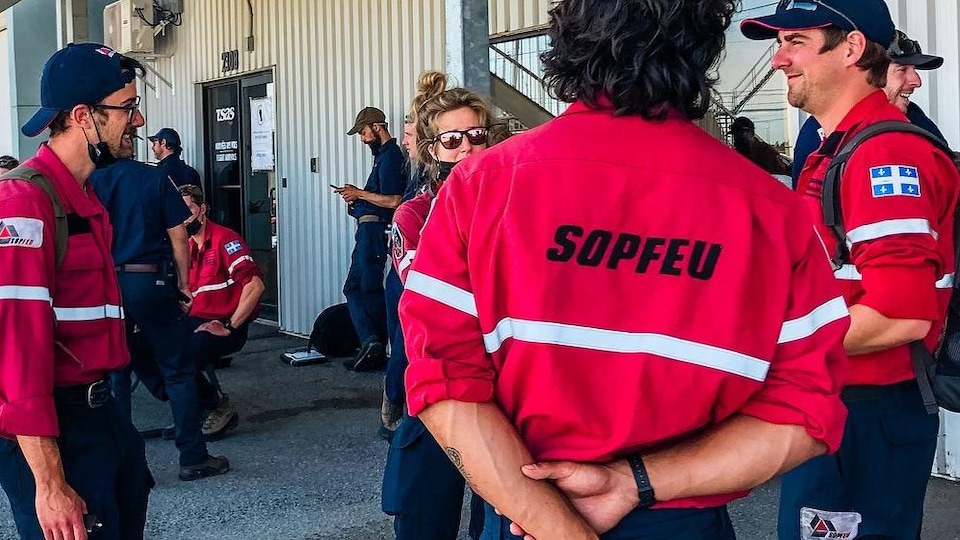 Des pompiers de la SOPFEU discutent ensemble et avec une collègue du Service de lutte contre les incendies de la Colombie-Britannique.
