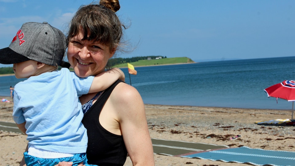 Sarah Green tient son fils dans ses bras sur la plage.
