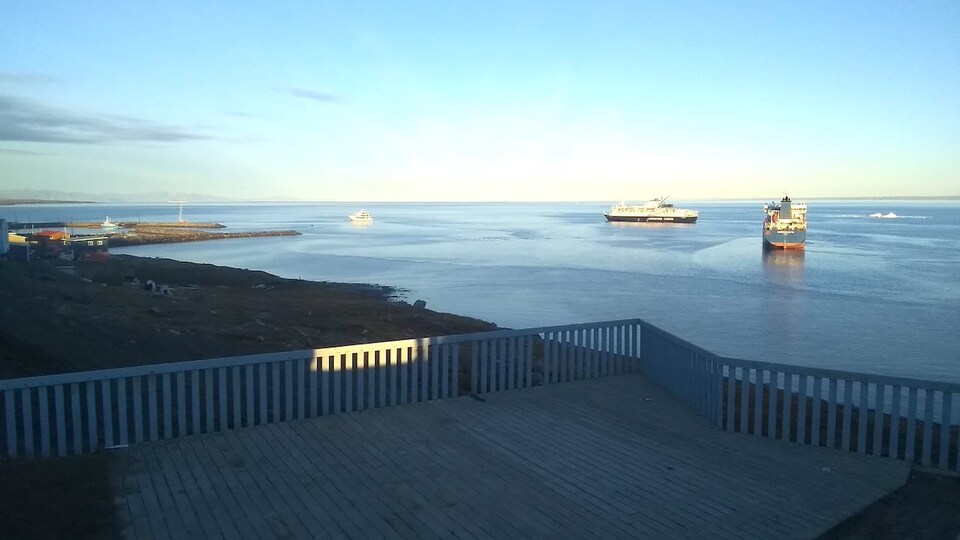 Un bateau et deux navires se trouvent au large devant le Centre des visiteurs Nattinak à Pond Inlet.