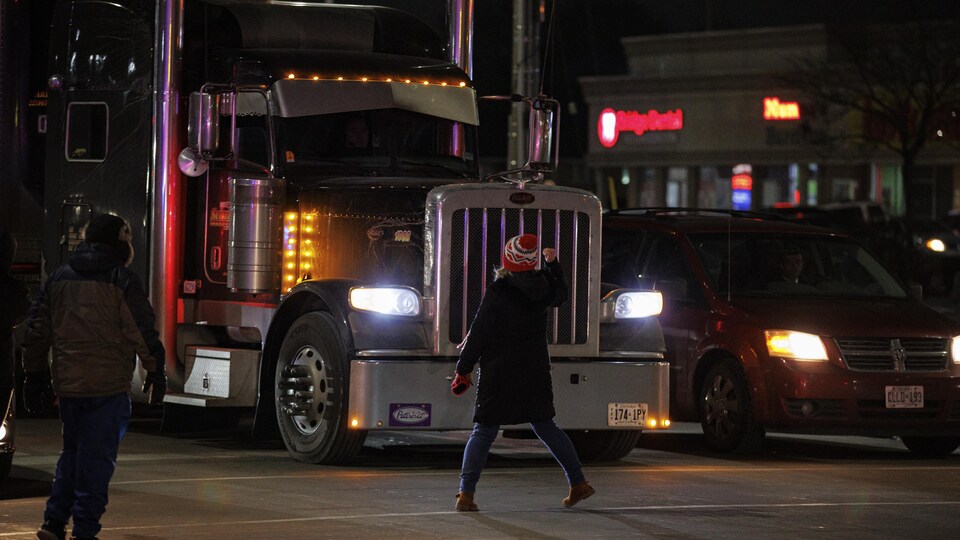 Une manifestante fait un geste devant un camion.