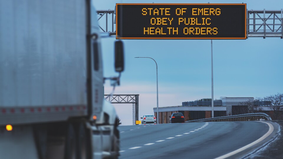 Un camion sur le pont s'apprête à passer sous l'affichage numérique d'un message rappelant l'état d'urgence.