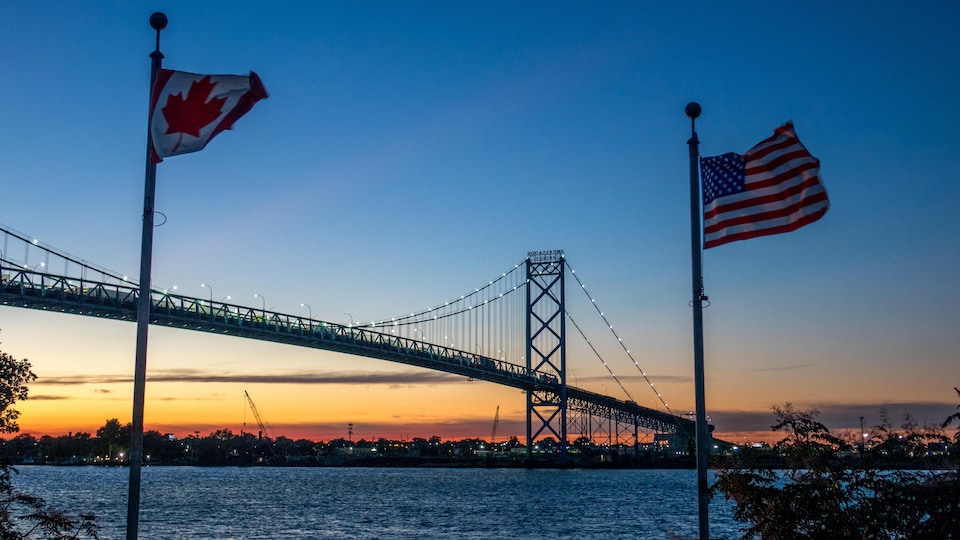 Une photo montre le pont Ambassadeur qui enjambe la rivière Détroit vu du côté de Windsor en Ontario avec les drapeaux canadien et américain.