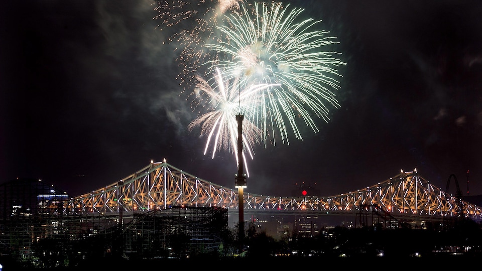 Un feu d'artifice éclate près du pont Jacques-Cartier, qui est illuminé, lors des célébrations du 375e de Montréal.