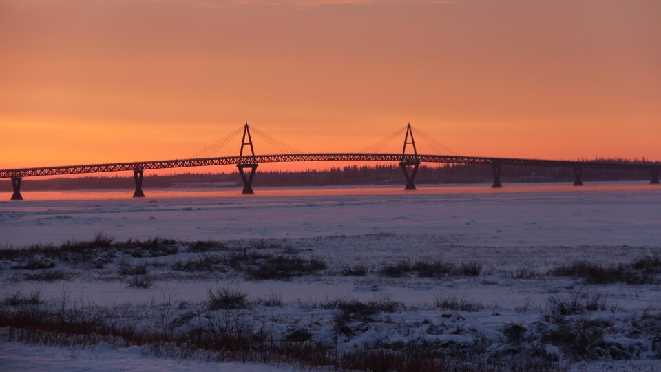 Vue de lever de soleil sur un pont qui enjambe un fleuve.
