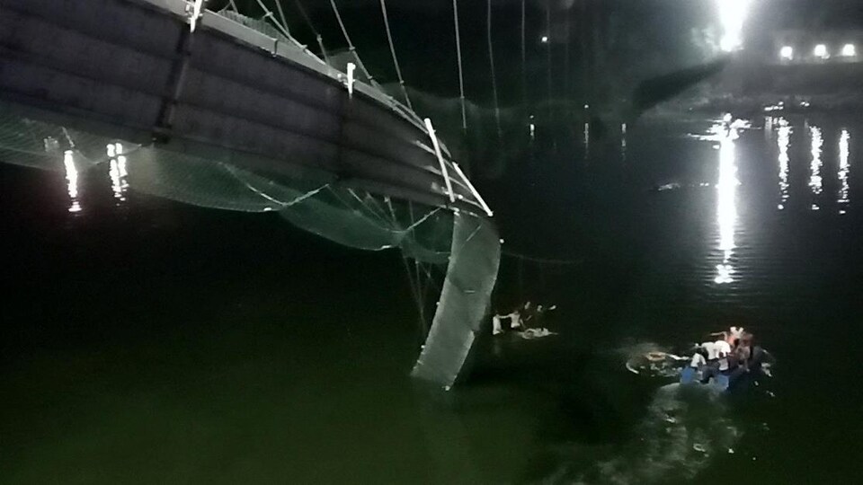 Une vue du pont en partie effondré. Des gens dans l'eau sont secourus par des personnes en bateau.