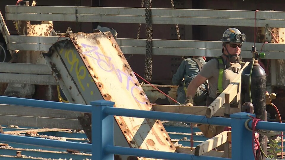 Un homme portant un casque et des lunettes de sécurité se trouve sur le pont dont des parties ont été enlevées.