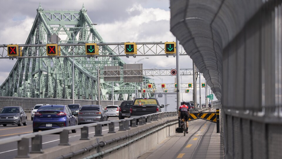 Un jeune homme en vélo arrive devant des barrières de ralentissement sur la piste cyclable du pont Jacques-Cartier.