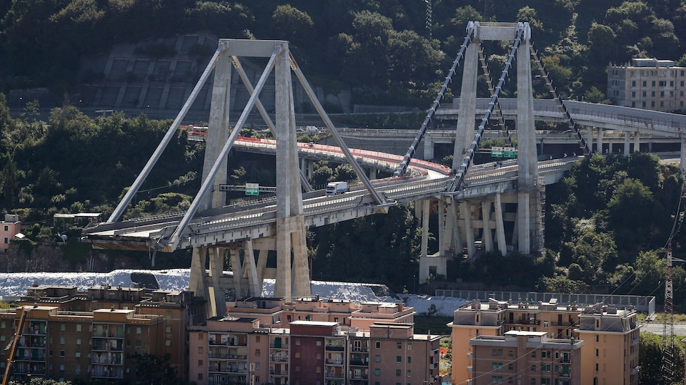 Un pont surplombant des bâtiments est photographié lors d'une journée ensoleillée. Une partie de ce pont est toutefois manquant.