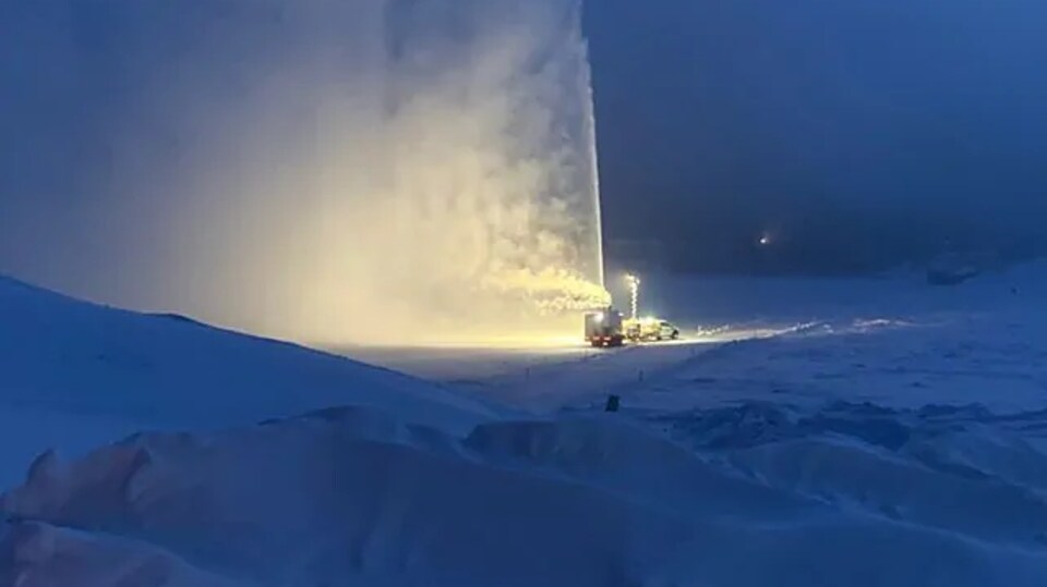 Une machine souffle de la neige en l'air lors de la construction d'un pont de glace près de Dawson.