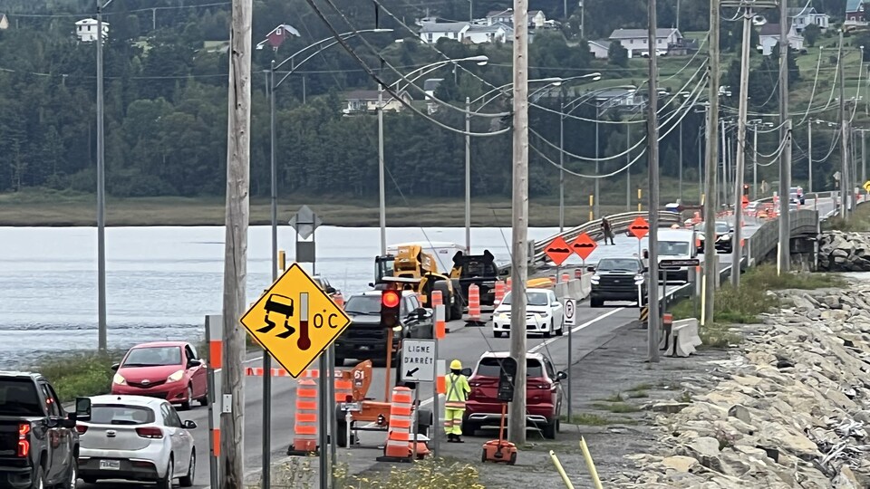 Automobiles qui traversent un pont dont la circulation est en partie entravée par des travaux.