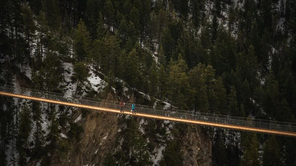 Deux personnes traversent le pont suspendu à 130 mètres du sol.
