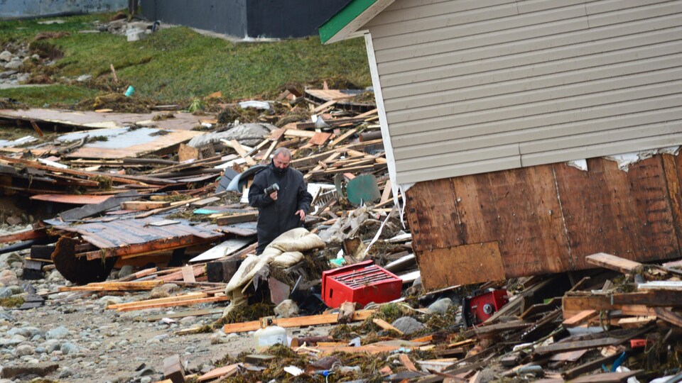 Un homme se trouve parmi les décombres d'une maison.