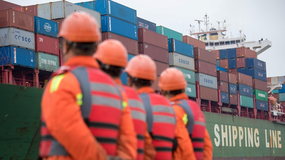 Des travailleurs regardent un cargo s'approcher d'un terminal au port de Qingdao, dans le Shandong.