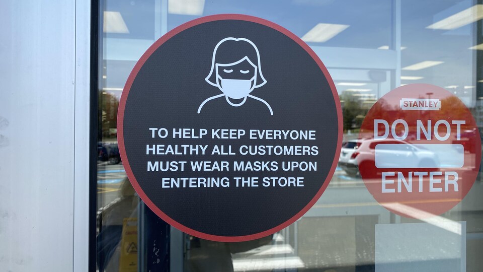 Un collant apposé sur la porte du magasin avertit la clientèle de l'obligation du port de masque.